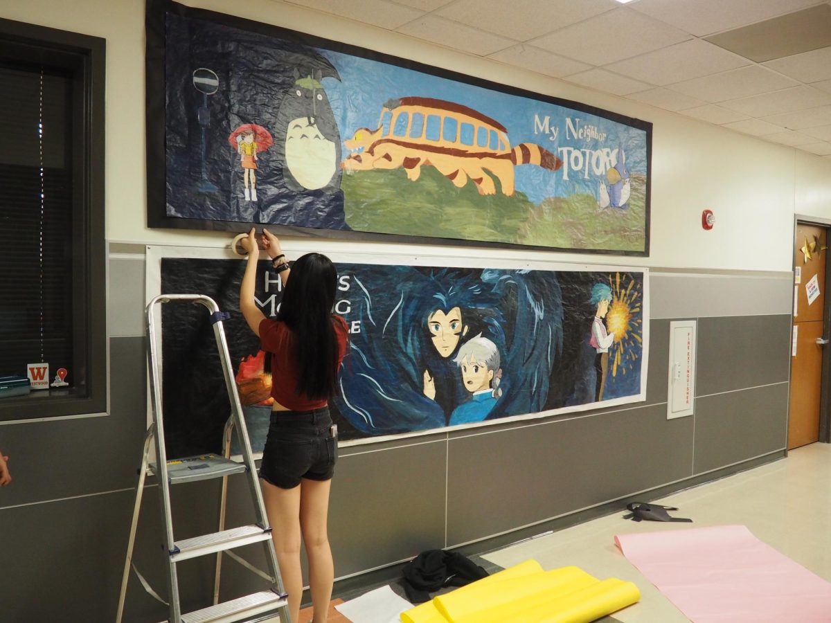 Attaching hand-painted banners to the hall outside of art classrooms, Sophia Huang '24 executes NAHS's vision for a Studio Ghibli themed hallway. NAHS members dedicated time and diligence into recreating elaborate scenes from popular Studio Ghibli films as part of their decorations.