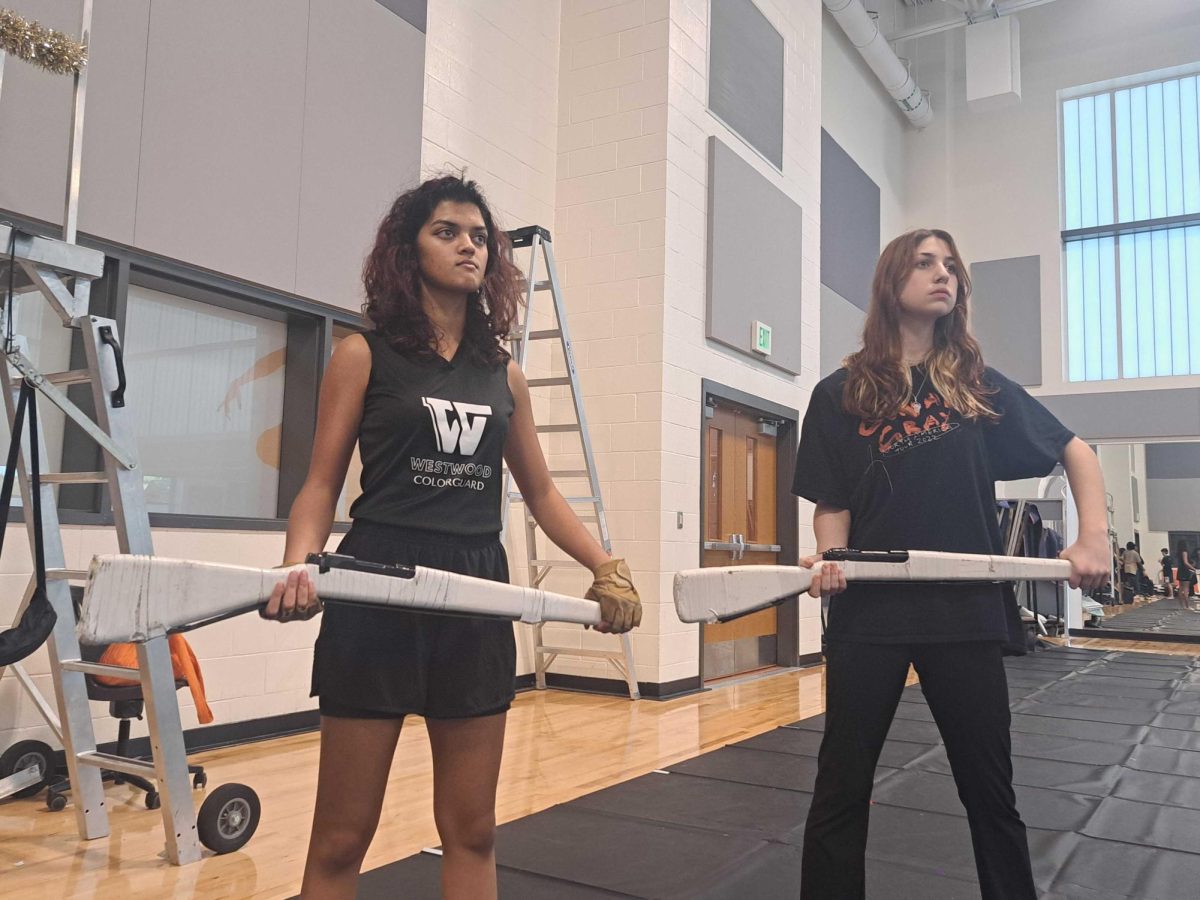Waiting for rehearsal to begin, color guard captains Ari Coulekar ‘24 and Keira Humphries ‘24 stand ready with their rifles to learn new choreography for their winter guard show. The captains have made sure the members of the Color Guard are ready to have a productive rehearsal and know what equipment to have. "The guard is very, very enthusiastic about everything right now," Coulekar said. "I remember at the show reveal, everybody was super excited about the show and suggesting things already even though it hadn’t even started yet."

