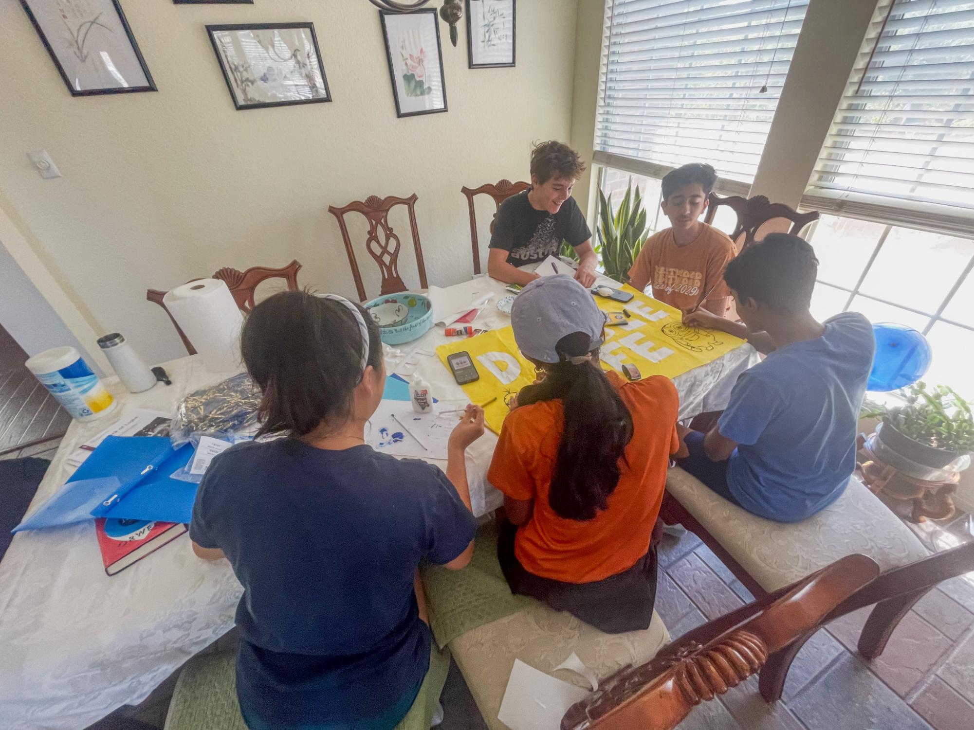 Crowding around the table, Student Council (StuCo) Freshman Class officers decorate the 'Despicable Me'-themed poster. Class officers decorated their float from 1 p.m. to 7 p.m. "We went for a big orange and blue theme, with balloons and confetti and minion foil balloons," StuCo Freshman Class Co-President Isaac Zhang said. "We want to make it super fun and flashy while being nice to look at."