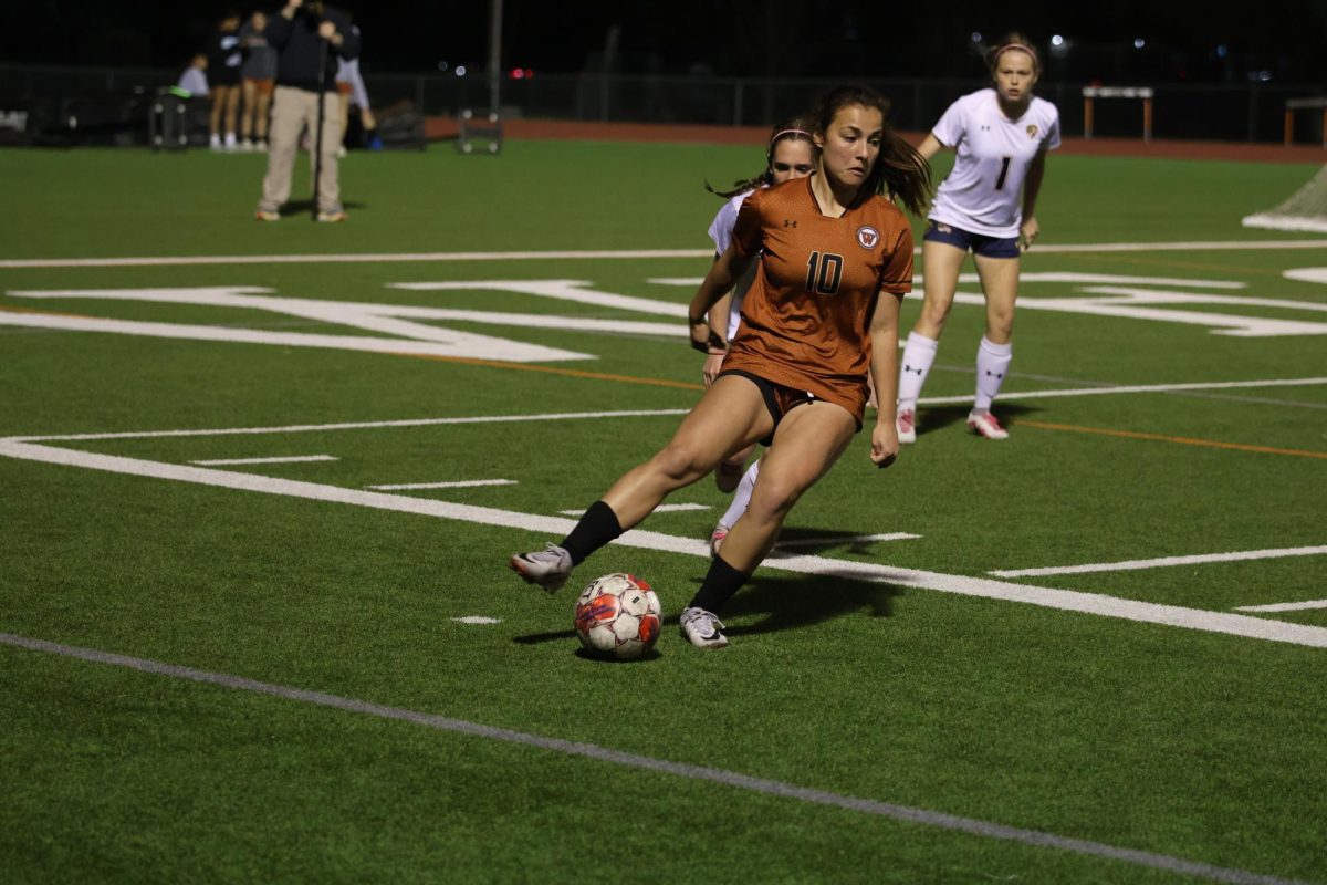 Crossing her leg over the ball, Mia Wiele '26 performs the scissors move. Throughout the game, she got around the Stony Point Tigers by faking them out with her moves.