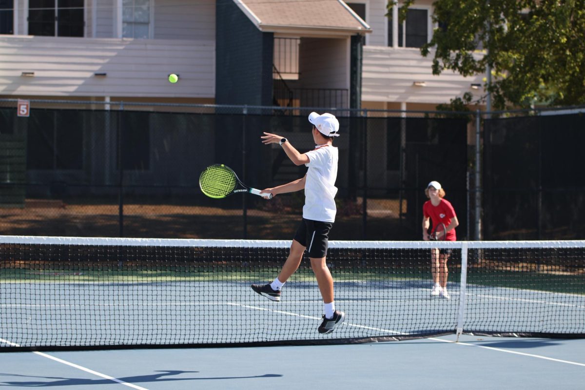 Brian Lee '27 soars to return a high lob with a forehand. Lee won this rally for his team but lost the match with a score of 7-8.