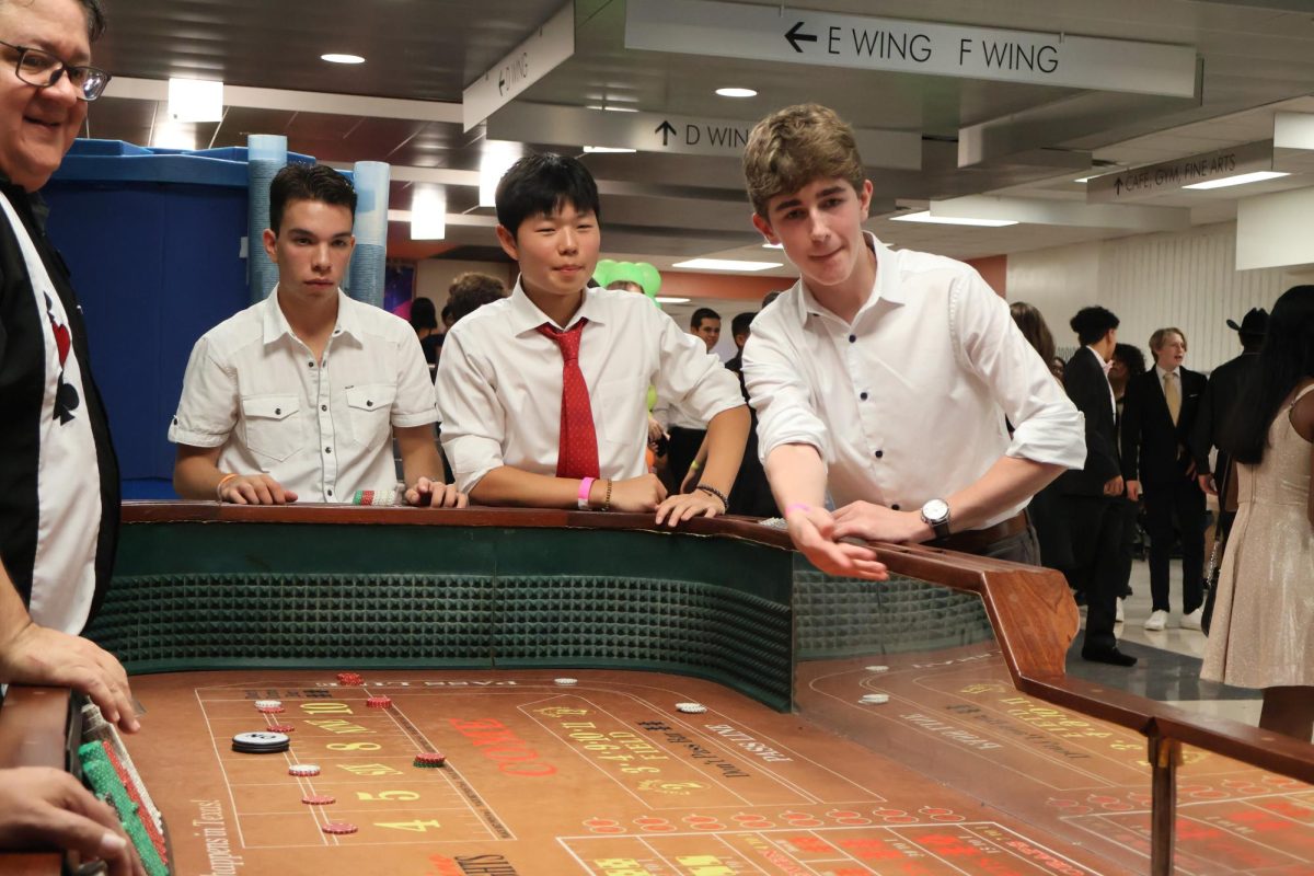 Playing casino games, Ryan Lee '25 and Coleman Loyd '25 enjoy their time at the Homecoming dance. Pacesetters brought casino tables to the atrium to offer a diverse selection of activities for students to participate in at the dance.