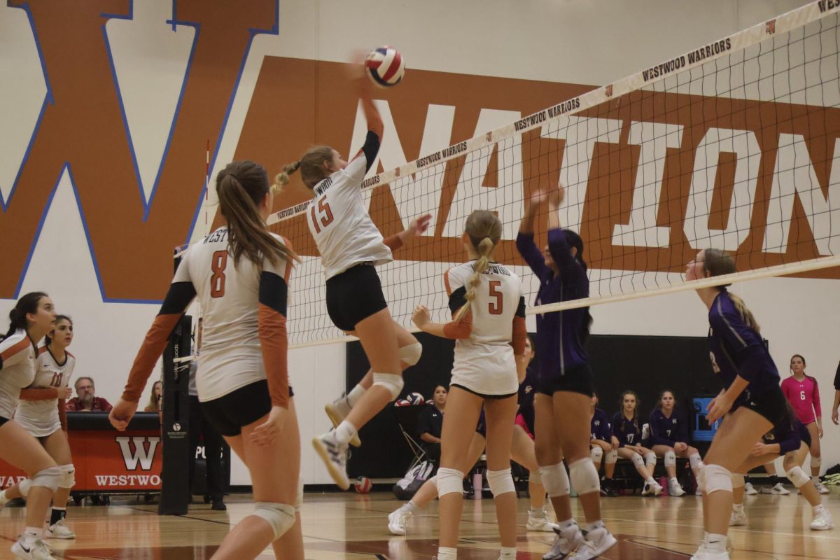 Emma Waghorne' 27 leaps to spike a ball down. Fleur Bullot' 27 set the ball up for Waghorne to hit. The rest of the team watches with anticipation waiting to see what will happen next. 